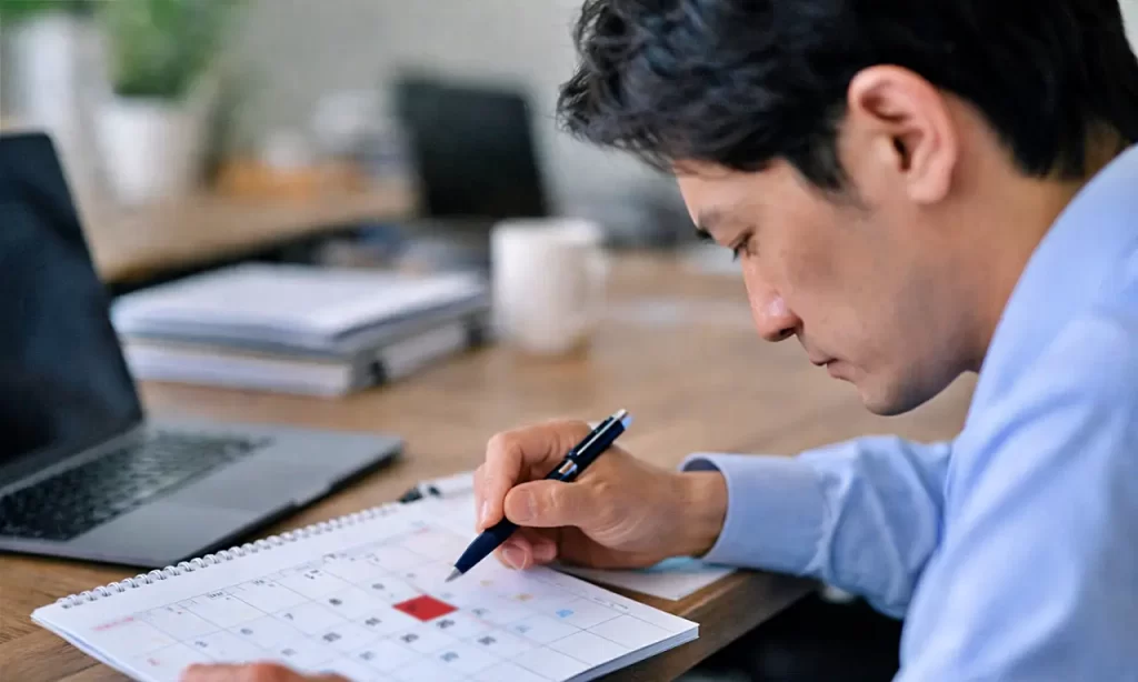 カレンダーにスケジュールを書き込む男性